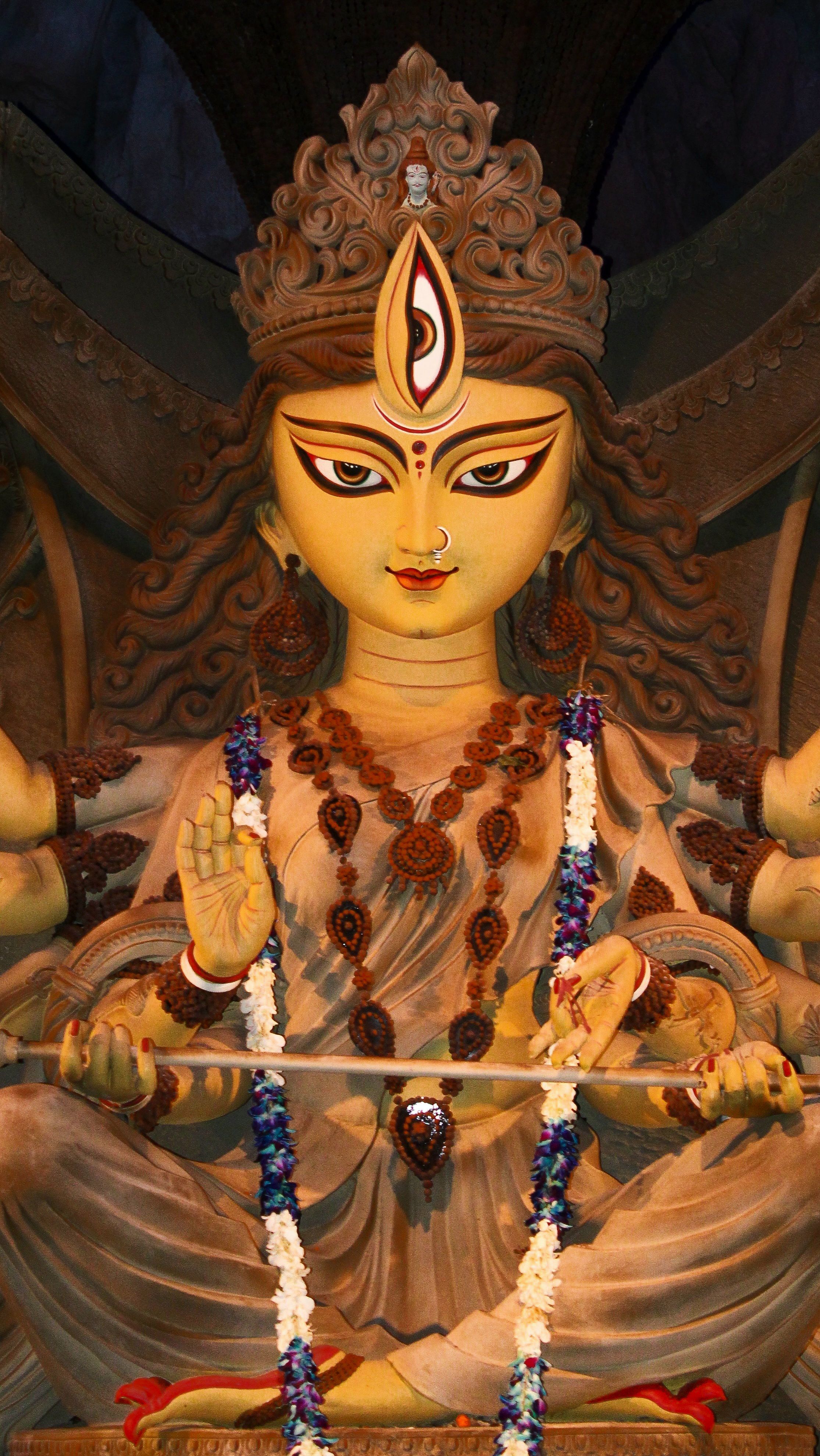 A sepia wood-carved Durga idol draped in rudraksha malas — photo via Pexels / Srinjoy Giri