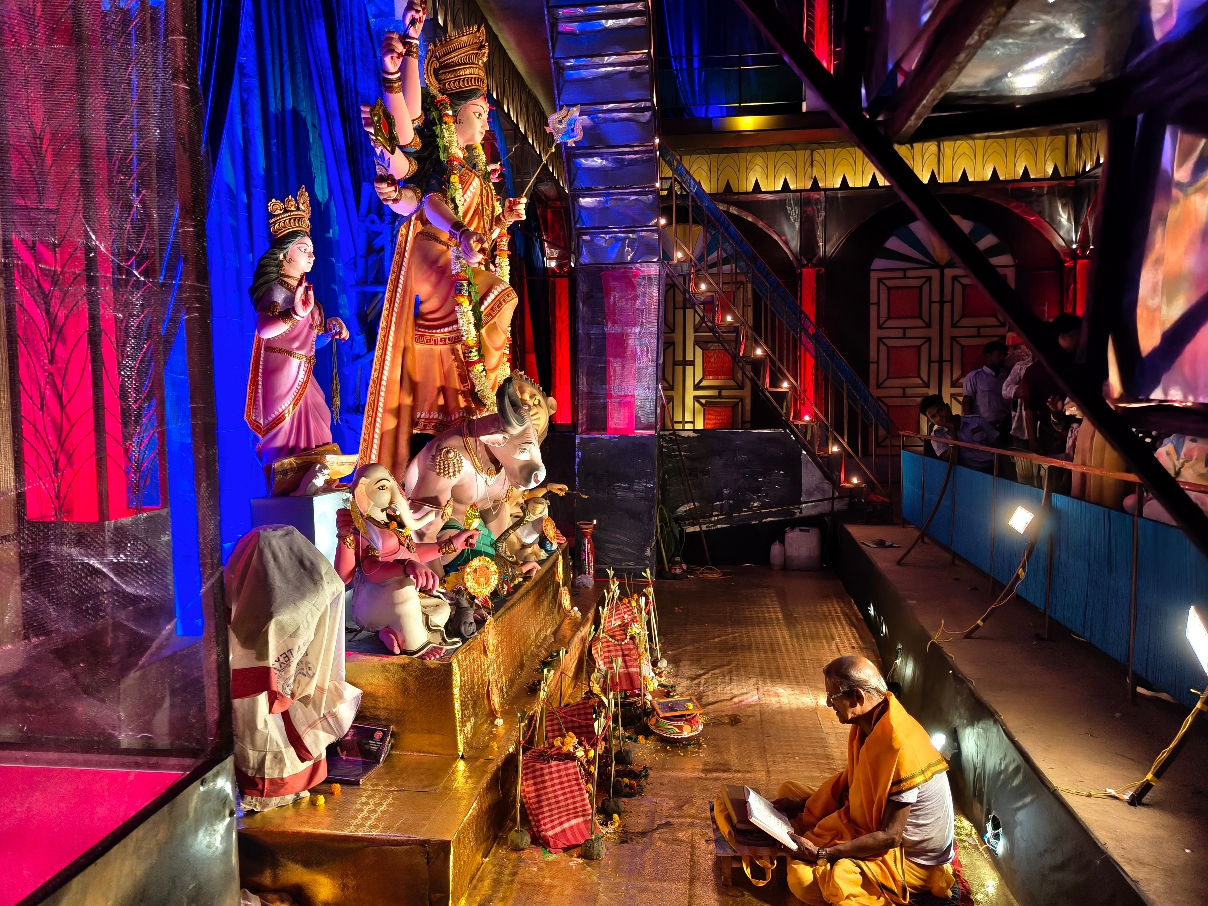 A priest reading scripture beside the idol inside a pandal — photo via Pexels / Trishik Bose