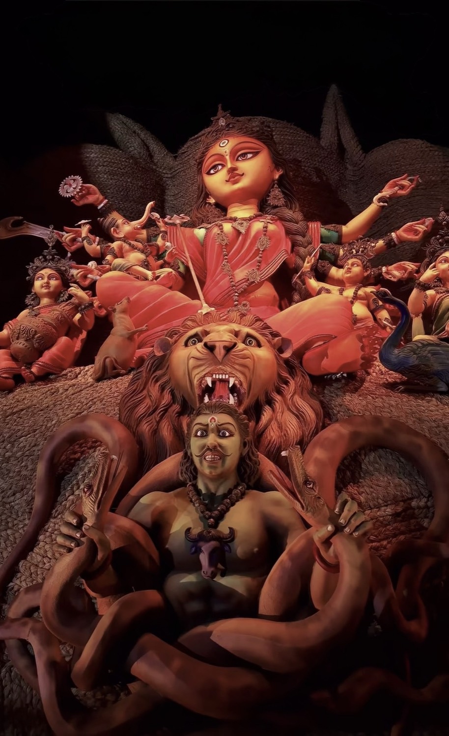 Durga atop her roaring lion, spear lowered, slaying Mahishasura the buffalo demon below
